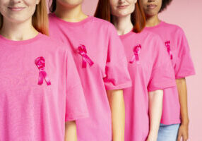 Group of women wearing pink t shirts with pink ribbons is showing support for breast cancer awareness